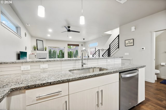 kitchen with sink, dark hardwood / wood-style floors, light stone counters, decorative light fixtures, and stainless steel dishwasher