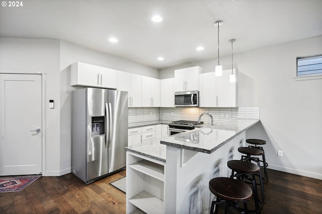 kitchen featuring pendant lighting, white cabinetry, stainless steel appliances, tasteful backsplash, and kitchen peninsula