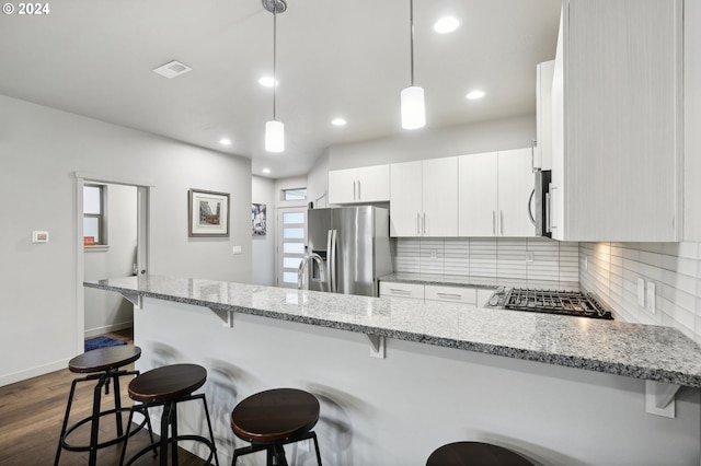 kitchen featuring white cabinets, hanging light fixtures, kitchen peninsula, stainless steel appliances, and light stone countertops