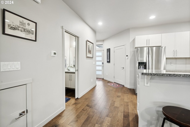 kitchen featuring backsplash, dark hardwood / wood-style flooring, white cabinets, light stone counters, and stainless steel fridge with ice dispenser