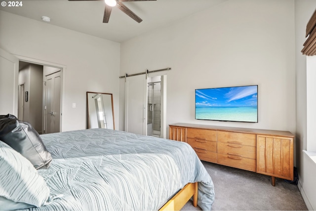 bedroom featuring ceiling fan, carpet flooring, a barn door, and ensuite bath