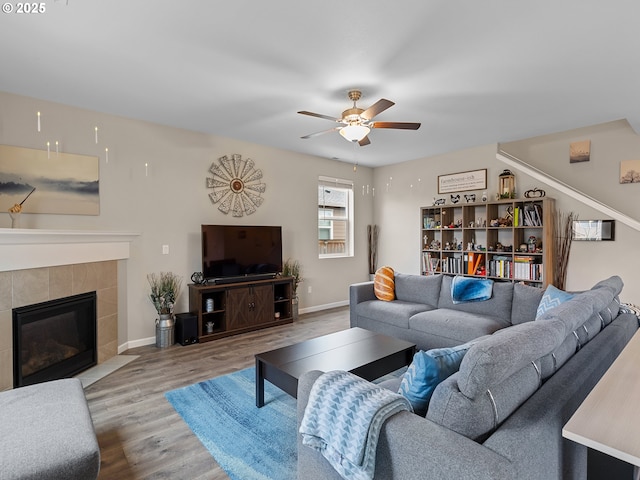 living room featuring ceiling fan, hardwood / wood-style floors, and a fireplace