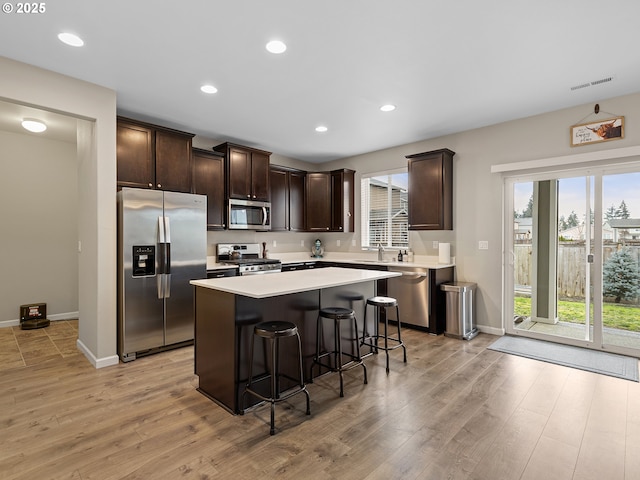 kitchen with light wood-type flooring, a kitchen breakfast bar, a center island, and appliances with stainless steel finishes