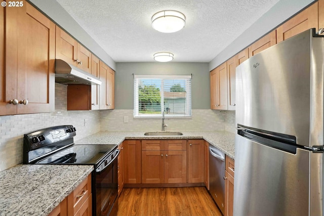 1208 SE Chapman Ave, Troutdale, OR 97060 - kitchen featuring appliances with stainless steel finishes, under cabinet range hood, light wood finished floors, a textured ceiling, and light stone countertops