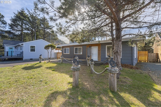 single story home with a wooden deck, a front yard, and fence