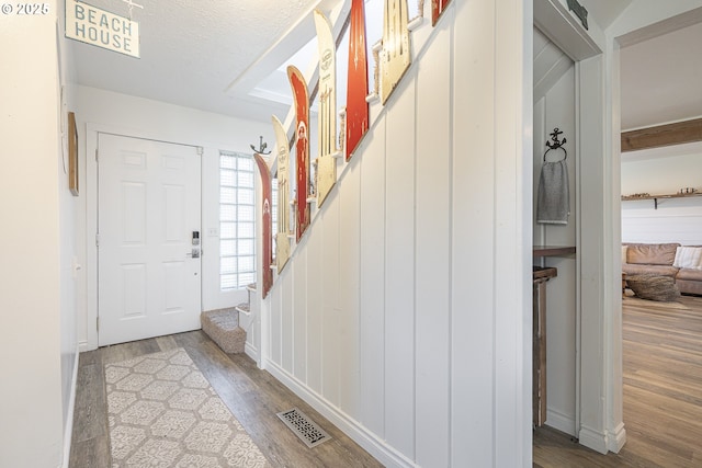 foyer with visible vents, stairs, and wood finished floors