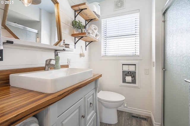 full bathroom with visible vents, vanity, wood finished floors, and a shower stall