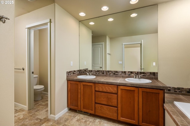 20937 SW Edgemont St, Beaverton, OR 97003 - bathroom with toilet, double vanity, tiled bath, recessed lighting, and baseboards