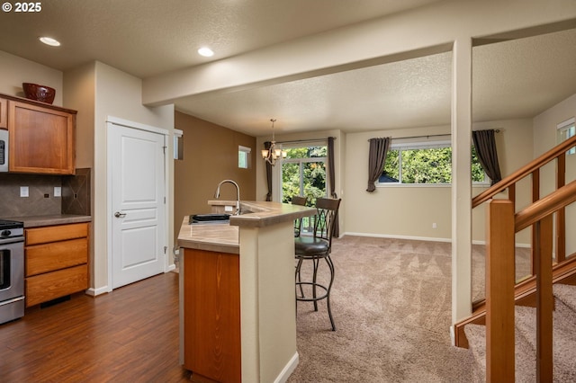 20937 SW Edgemont St, Beaverton, OR 97003 - kitchen featuring a sink, brown cabinetry, a kitchen breakfast bar, white microwave, and a textured ceiling