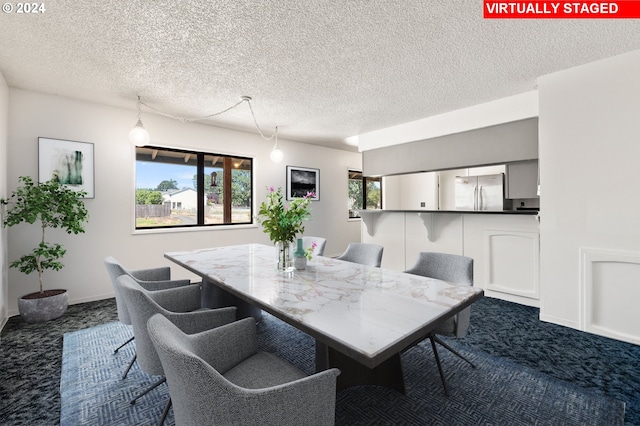 carpeted dining space featuring a healthy amount of sunlight and a textured ceiling