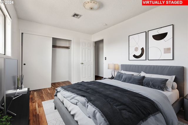 bedroom with a closet, dark hardwood / wood-style floors, and a textured ceiling