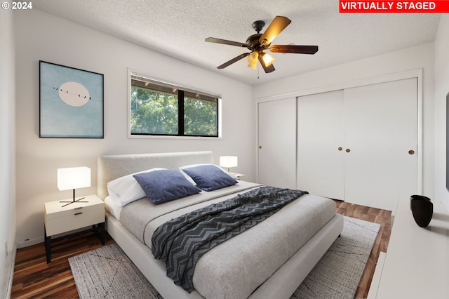 bedroom with ceiling fan, a textured ceiling, dark hardwood / wood-style flooring, and a closet