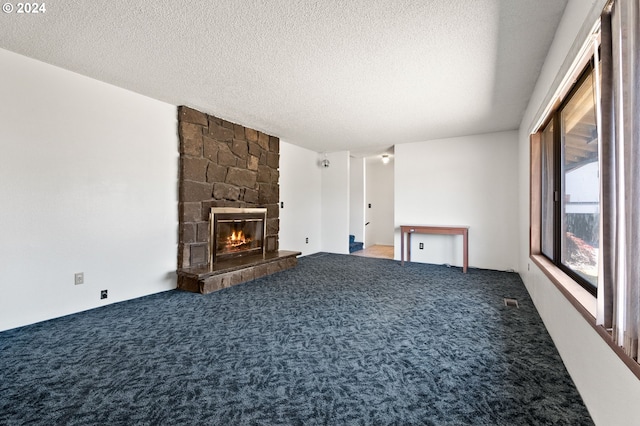 unfurnished living room with carpet floors, a textured ceiling, and a stone fireplace