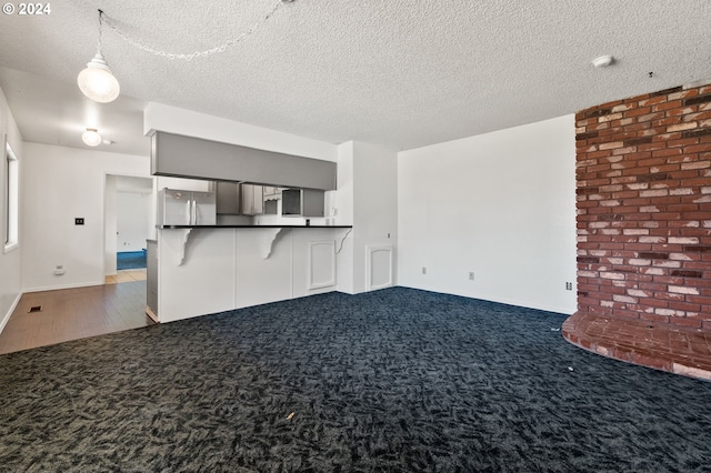 unfurnished living room with dark carpet and a textured ceiling