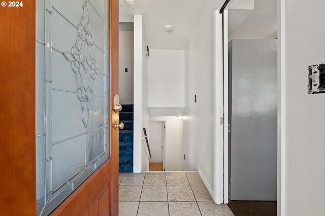 interior space with a textured ceiling and light tile patterned flooring