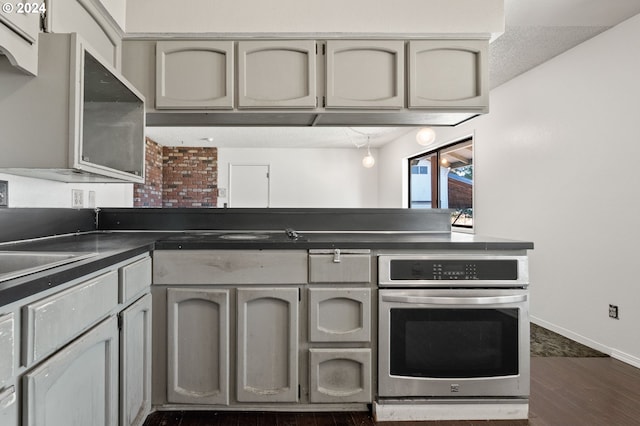 kitchen featuring dark wood-type flooring, gray cabinets, sink, and oven