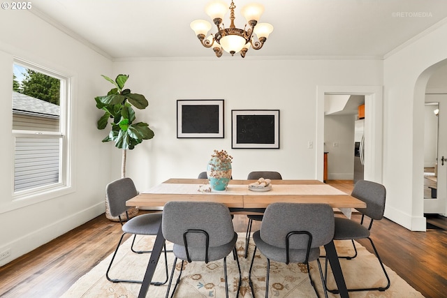 5125 NE Davis St, Portland, OR 97213 - dining area with arched walkways, ornamental molding, a chandelier, wood finished floors, and baseboards