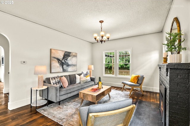 5125 NE Davis St, Portland, OR 97213 - living area featuring dark wood finished floors, arched walkways, a chandelier, baseboards, and a textured ceiling