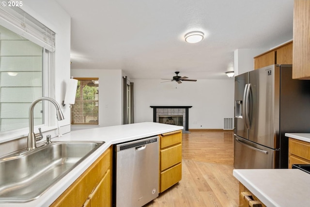 kitchen featuring a sink, ceiling fan, light countertops, stainless steel appliances, and light wood-style floors