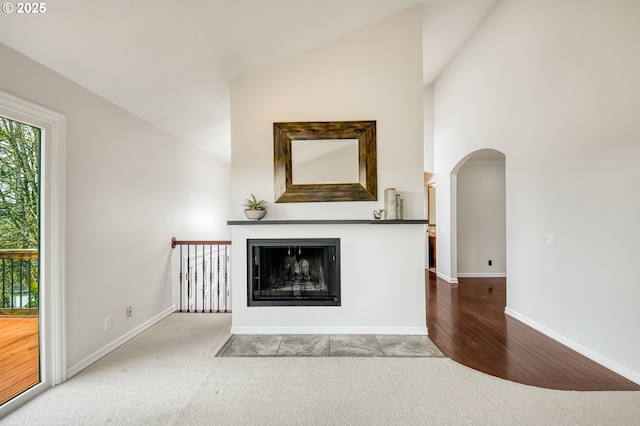 1610 Lee St, Lake Oswego, OR 97034 - unfurnished living room featuring arched walkways, carpet floors, a fireplace with flush hearth, lofted ceiling, and baseboards