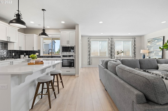 living room featuring light wood-style floors, baseboards, and recessed lighting