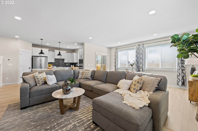 living room with baseboards, recessed lighting, and light wood-style flooring