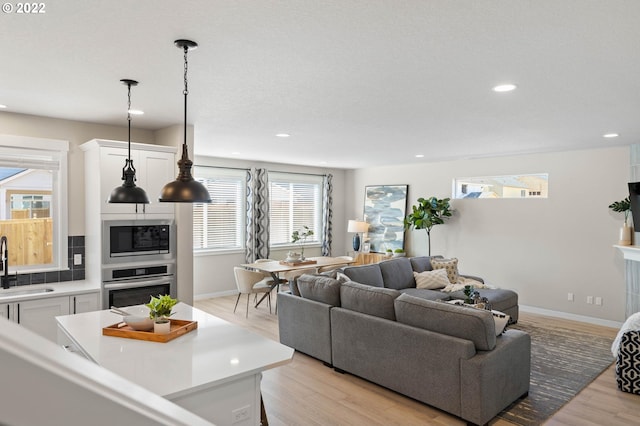 living room with baseboards, recessed lighting, and light wood-style flooring