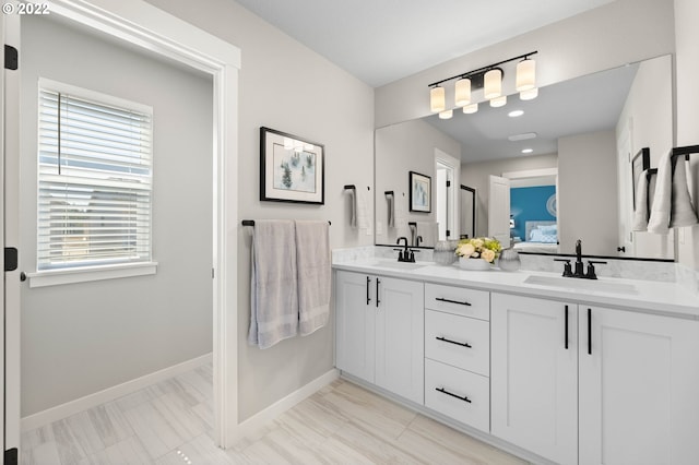 full bath with double vanity, baseboards, a sink, and ensuite bathroom
