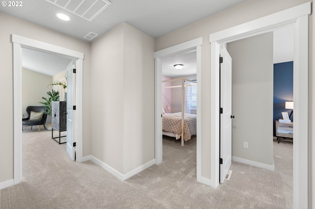 hallway featuring carpet floors, baseboards, and visible vents