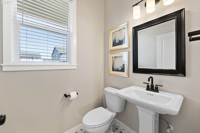 bathroom with toilet, baseboards, a sink, and marble finish floor