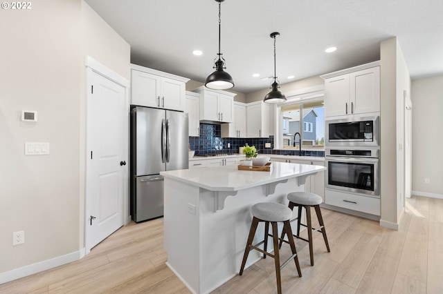 kitchen with a sink, stainless steel appliances, baseboards, decorative backsplash, and a kitchen island