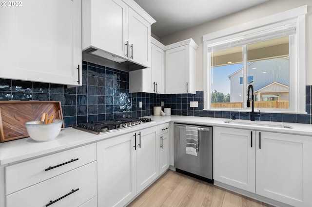 kitchen with white cabinets, stainless steel appliances, a sink, and tasteful backsplash