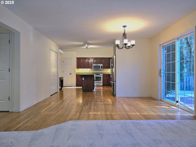 kitchen featuring a kitchen island, pendant lighting, a notable chandelier, stainless steel appliances, and dark brown cabinets