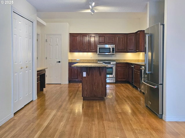 kitchen featuring dark brown cabinetry, a breakfast bar, a kitchen island, hardwood / wood-style flooring, and stainless steel appliances