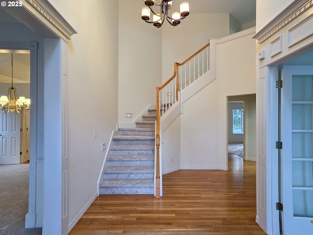 stairway featuring hardwood / wood-style floors, a chandelier, and a high ceiling