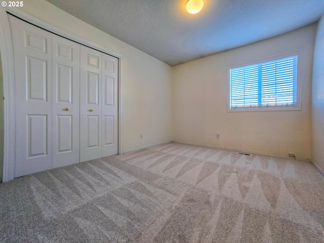 unfurnished bedroom with a closet, light carpet, and a textured ceiling