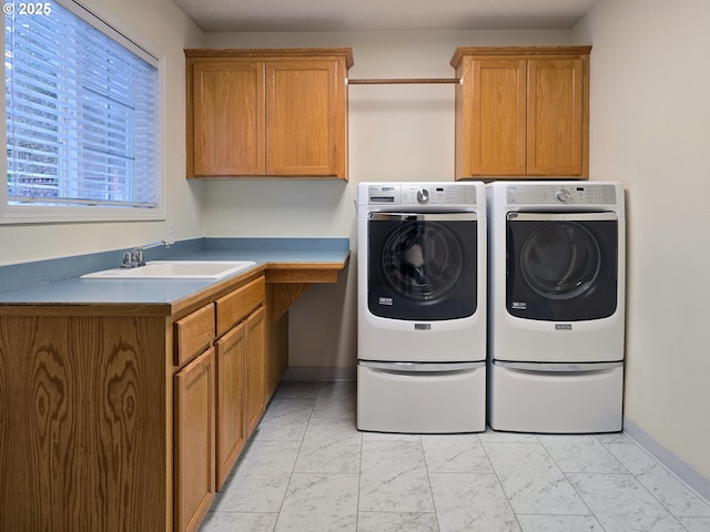 laundry area featuring cabinets, sink, and washer and clothes dryer