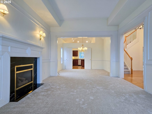 unfurnished living room with a fireplace, carpet, and a notable chandelier