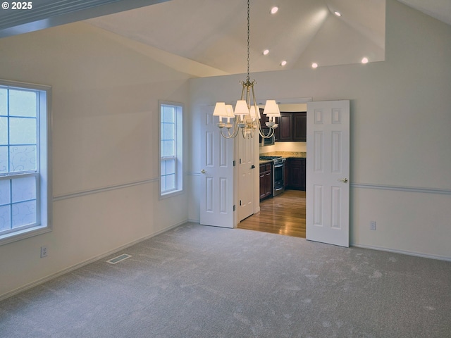 carpeted spare room with plenty of natural light, lofted ceiling, and a notable chandelier