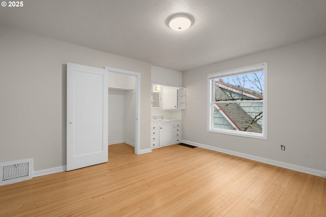 646 SE 60th Ave, Portland, OR 97215 - unfurnished bedroom with a walk in closet, baseboards, light wood-type flooring, visible vents, and a closet