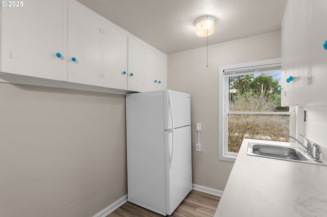 646 SE 60th Ave, Portland, OR 97215 - kitchen featuring a sink, light countertops, white cabinets, freestanding refrigerator, and light wood-style flooring