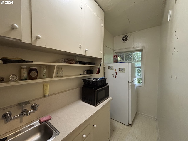 646 SE 60th Ave, Portland, OR 97215 - kitchen featuring freestanding refrigerator, black microwave, light countertops, white cabinets, and a sink