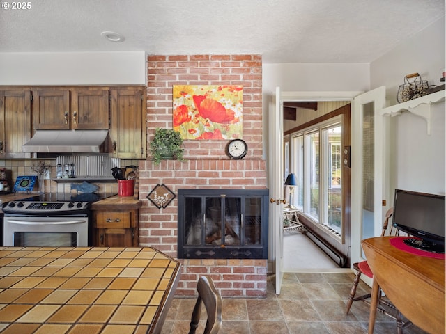 13513 SE 132nd Ave, Clackamas, OR 97015 - kitchen featuring stainless steel range with electric stovetop, tile counters, under cabinet range hood, a textured ceiling, and a fireplace