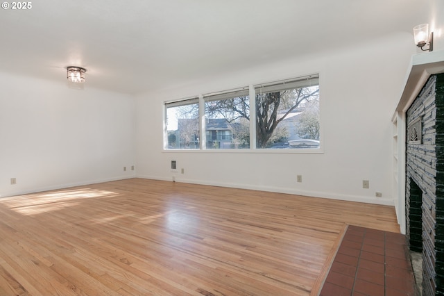 unfurnished living room with a brick fireplace and light hardwood / wood-style floors