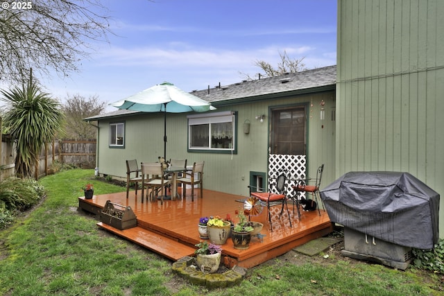 deck featuring grilling area, a yard, outdoor dining space, and fence