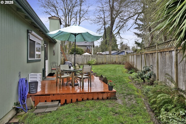 view of yard featuring a wooden deck, outdoor dining area, and a fenced backyard