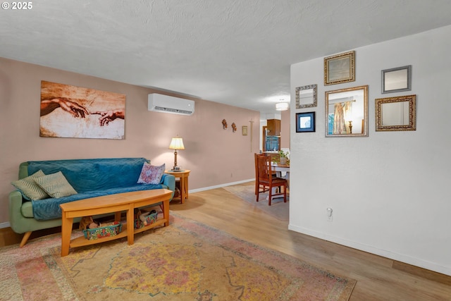 living area featuring baseboards, a textured ceiling, an AC wall unit, and wood finished floors