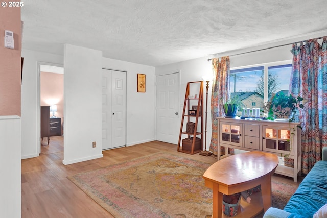 living room with a textured ceiling, baseboards, and wood finished floors