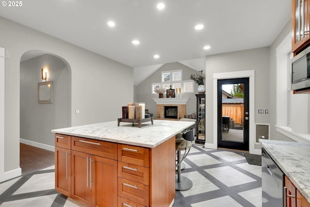 kitchen with a center island, baseboards, a breakfast bar, recessed lighting, and arched walkways