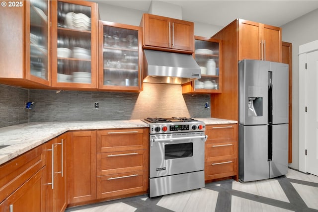 kitchen with brown cabinetry, decorative backsplash, ventilation hood, and stainless steel appliances